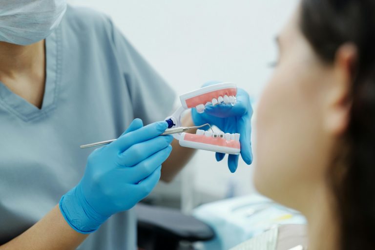dentist pointing to a specific tooth on a teeth model while a patient listens