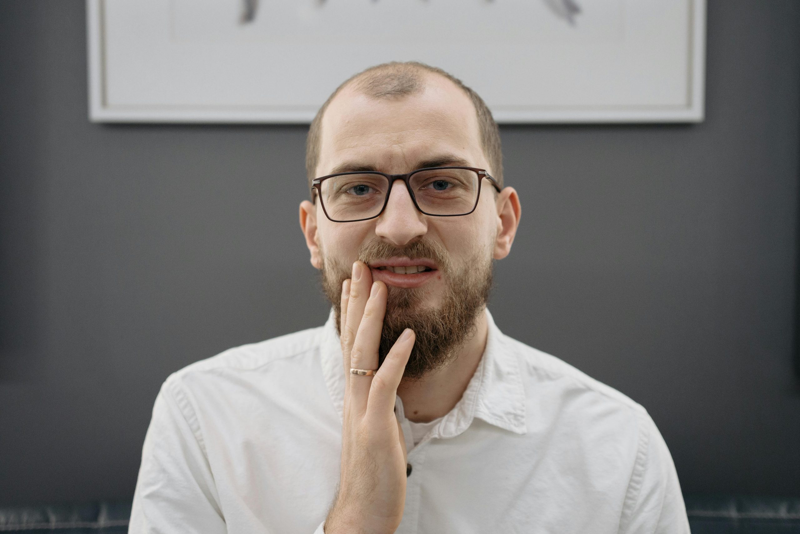 man with a worried expression touching the side of his mouth with his hand, indicating pain